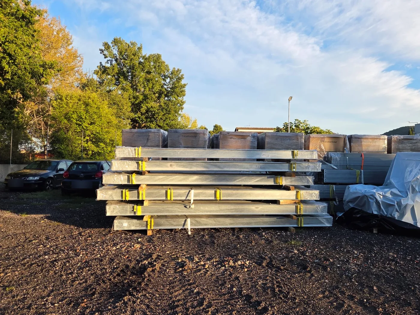 Profilati zincati impilati davanti ai bancali di moduli fotovoltaici nel cantiere di Ceprano
